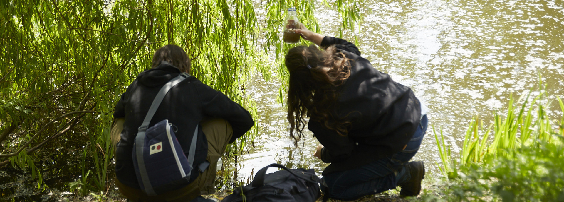 Two people collective water samples from a pond