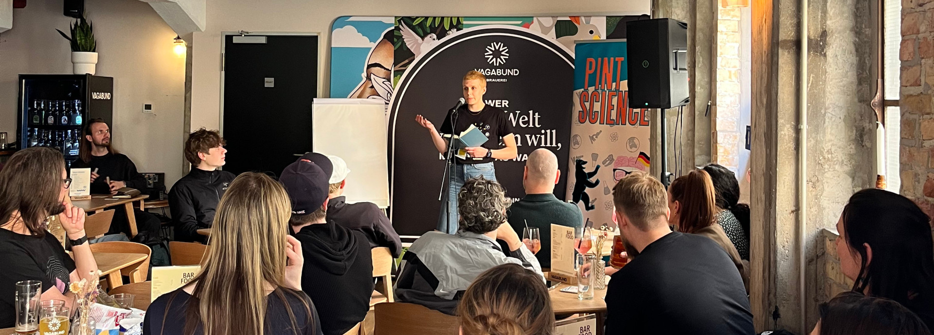 Scientist gives talk in front of crowd in a bar.