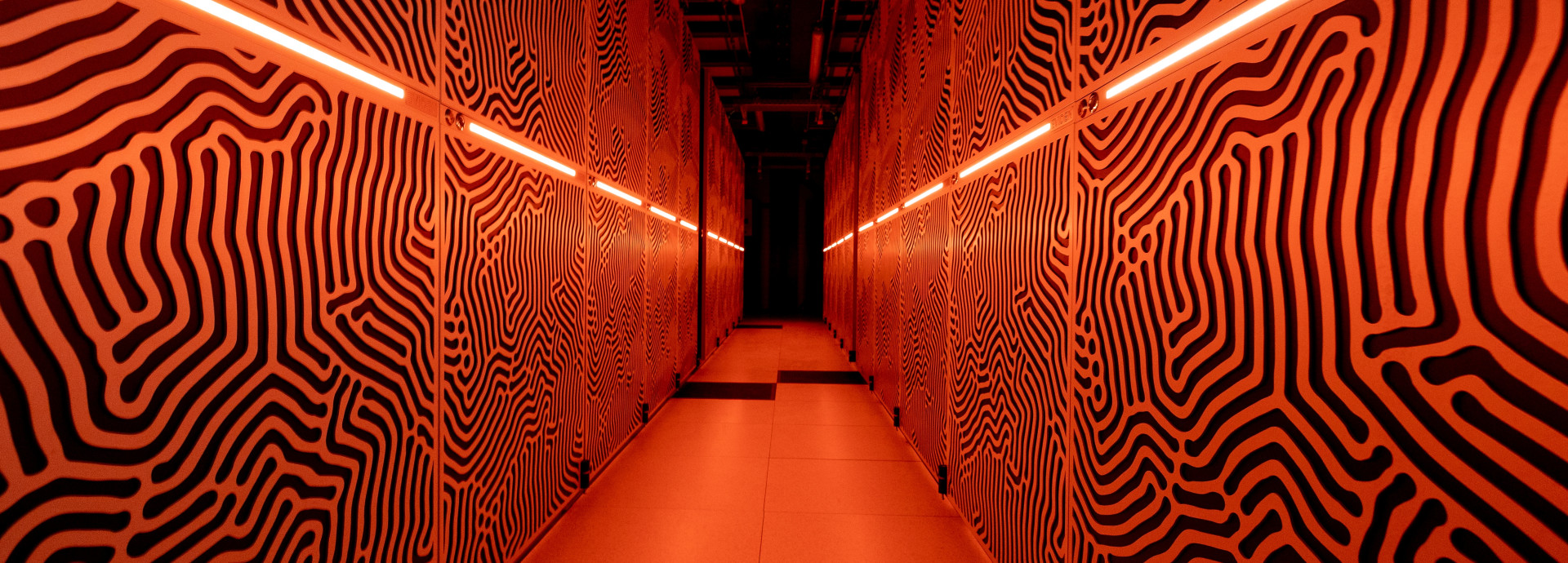Die Rechnerschränke unseres Supercomputers „JUPITER” sind in orangem Licht getaucht.