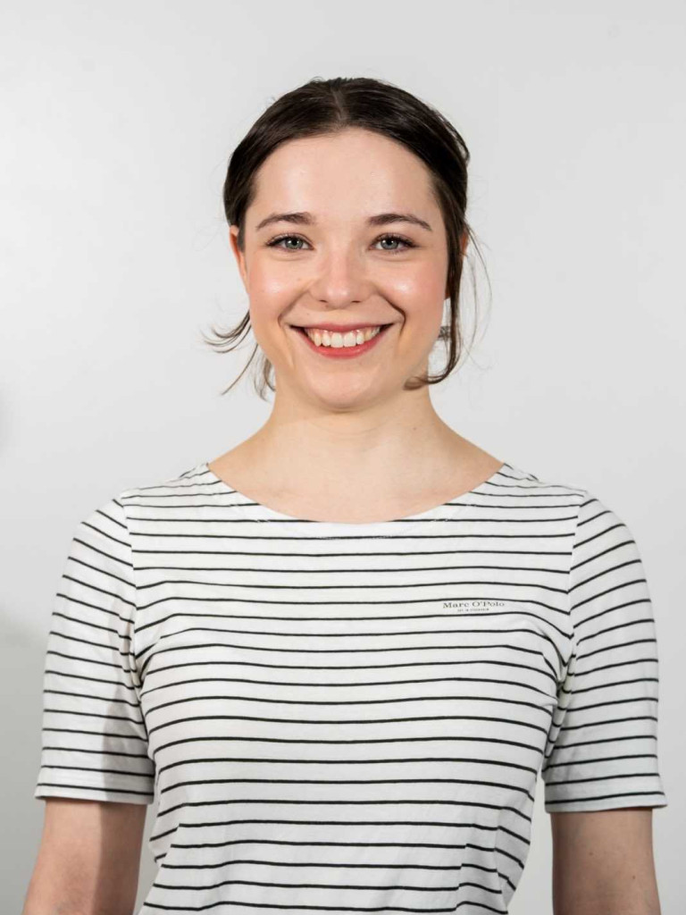 Porträt der Moderatorin Felina Czycykowski mit einem gestreiftem Oberteil vor einer hellen Wand