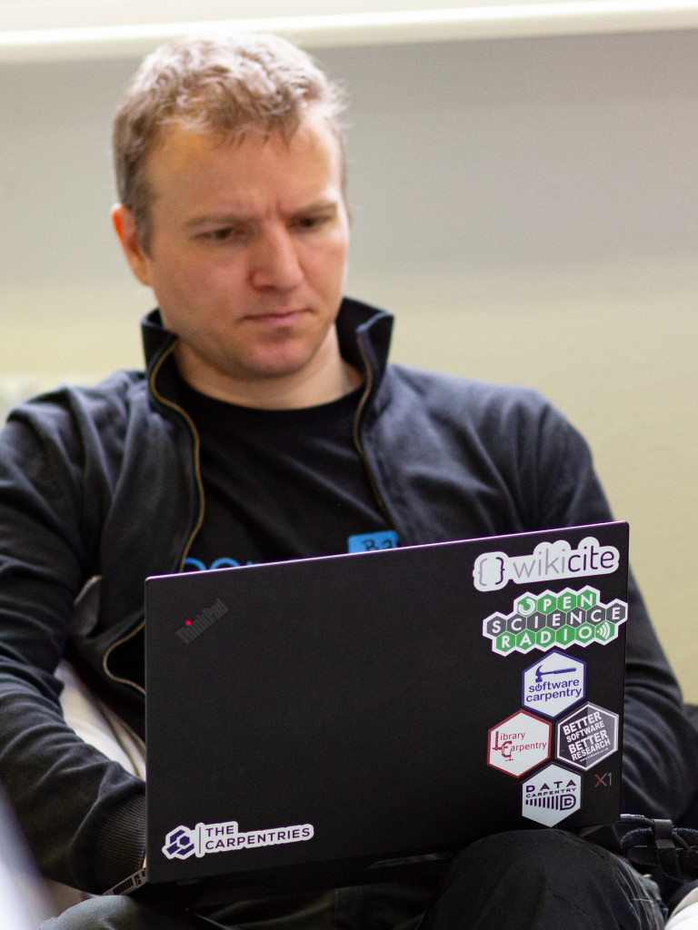 a person having a laptop on his lap with some stickers on