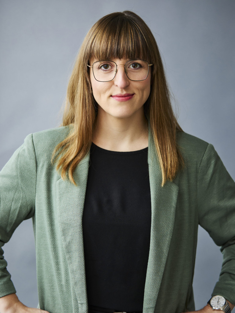 A woman with long hair and glasses standing