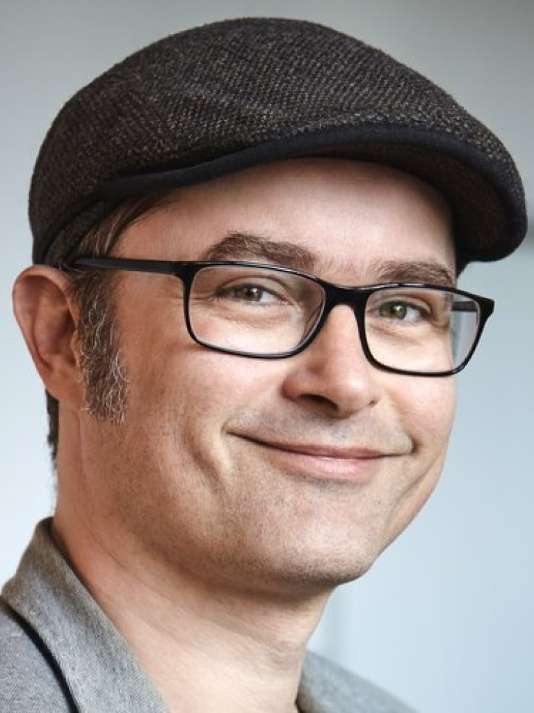 A white man wearing glasses and a hat.