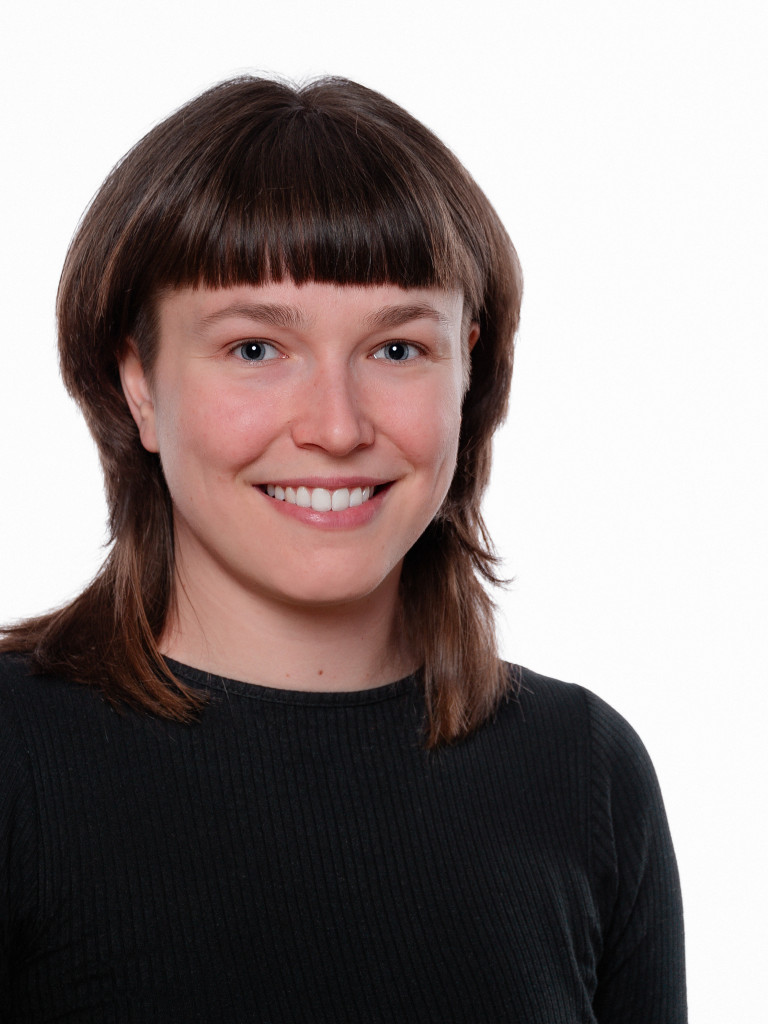 Anna Timofeeva wearing a black sweater, smiling at the camera.