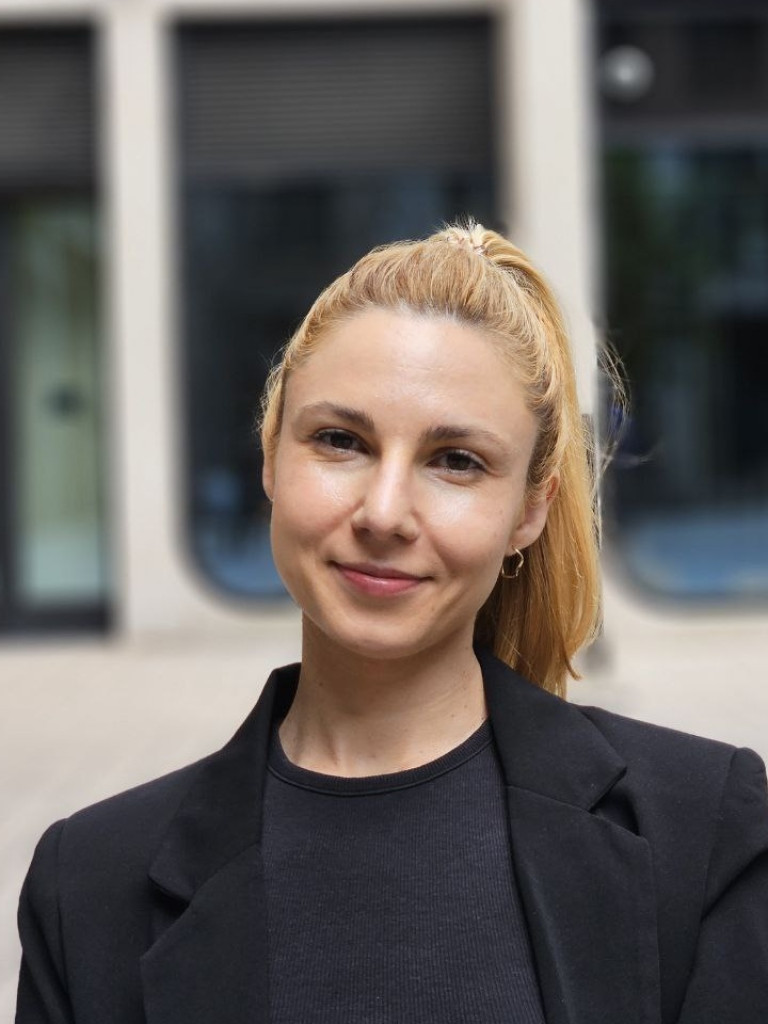 Jelena Brasanac is standing outside a building, wearing a black top and a black blazer and her hair in a pony tail.