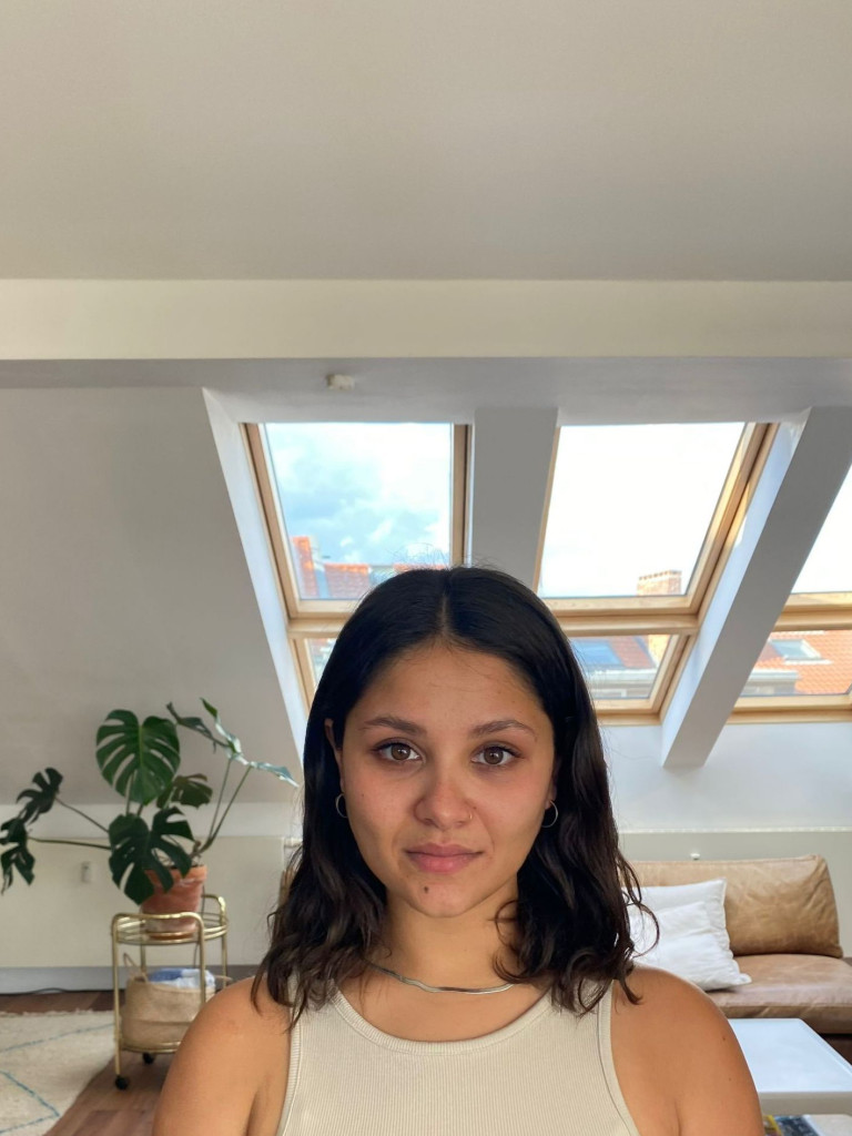 Manisha Haag is sitting in a bright living room, looking straight at the camera.