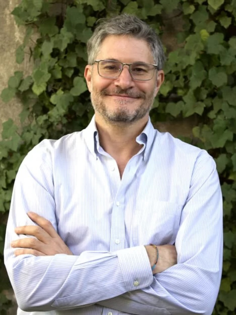 Speaker looking at camera in a white collared shirt.