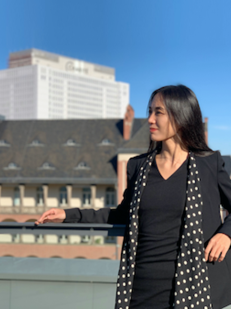 Frau auf einem Dach vor einem Geländer im Hintergrund das Gebäude der Charité Berlin