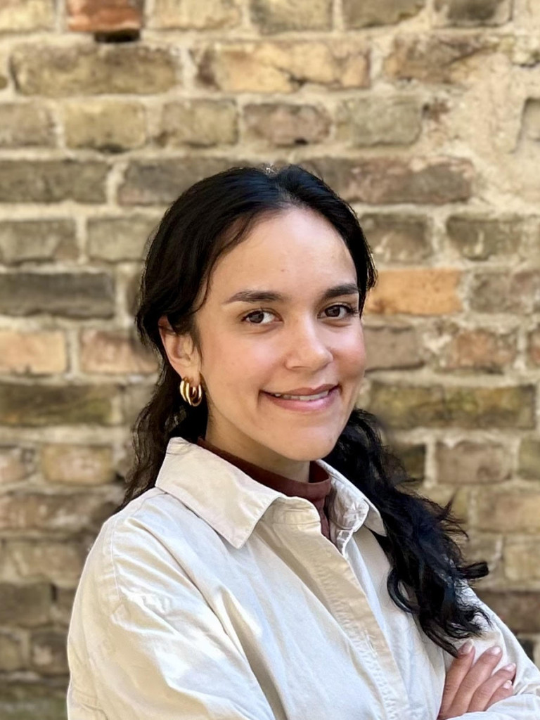 A professional headshot of Tara Merk, smiling and dressed in a white button-up shirt.