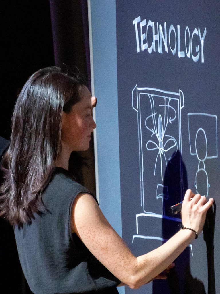 Woman drawing on chalk board.