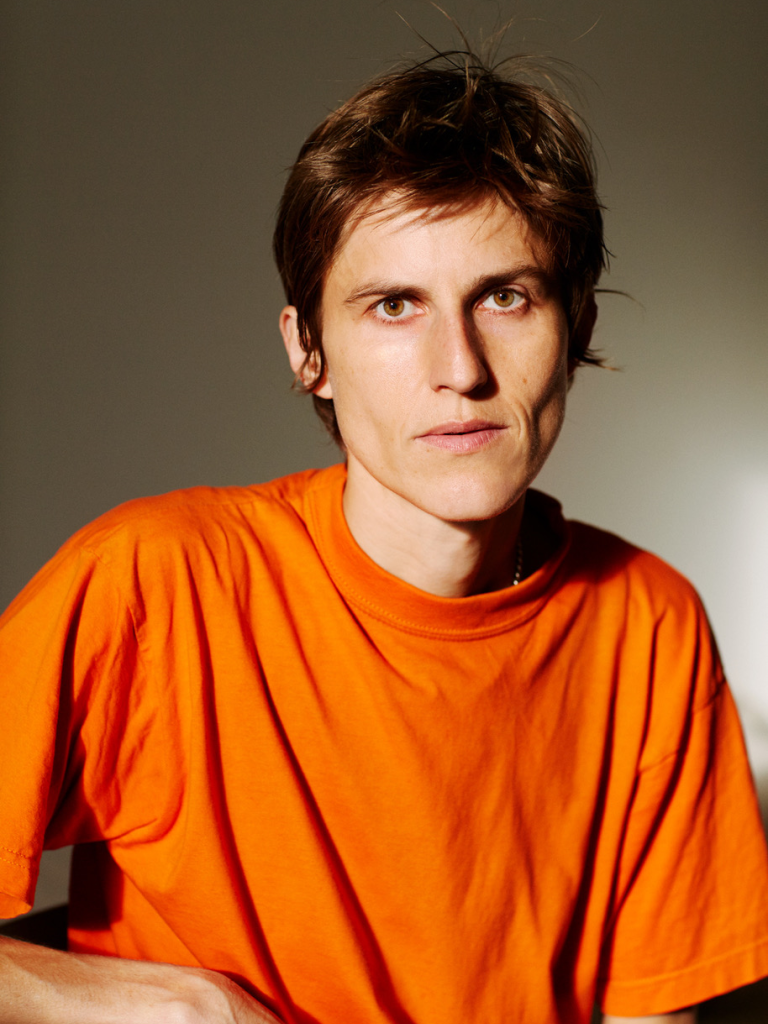 Anna Zett in orangem T-Shirt schaut in die Kamera