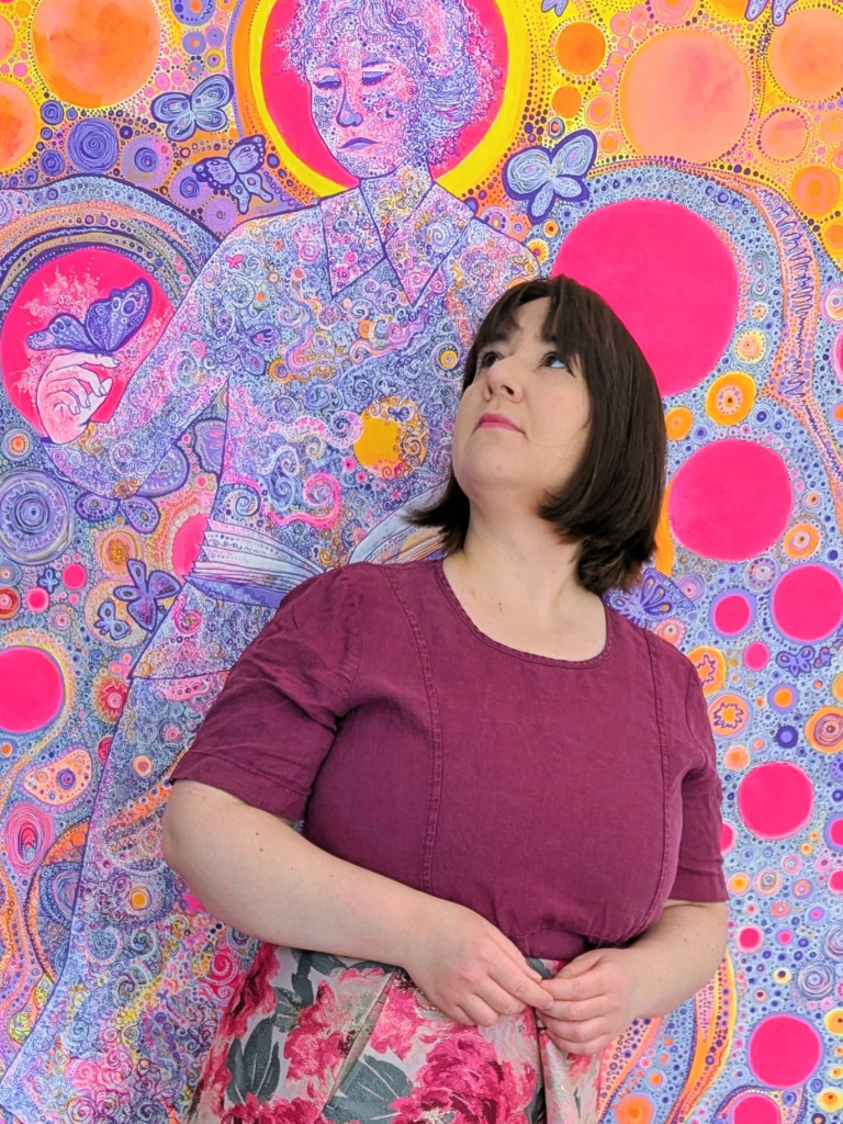 Portrait of a woman in a purple dress standing in front of a large colourful painting