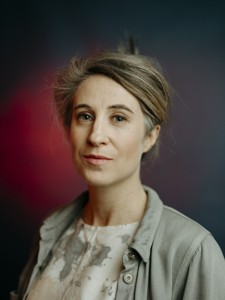 head and shoulders portrait photo of Jemma Woolmore aganist a drak grey and red background.