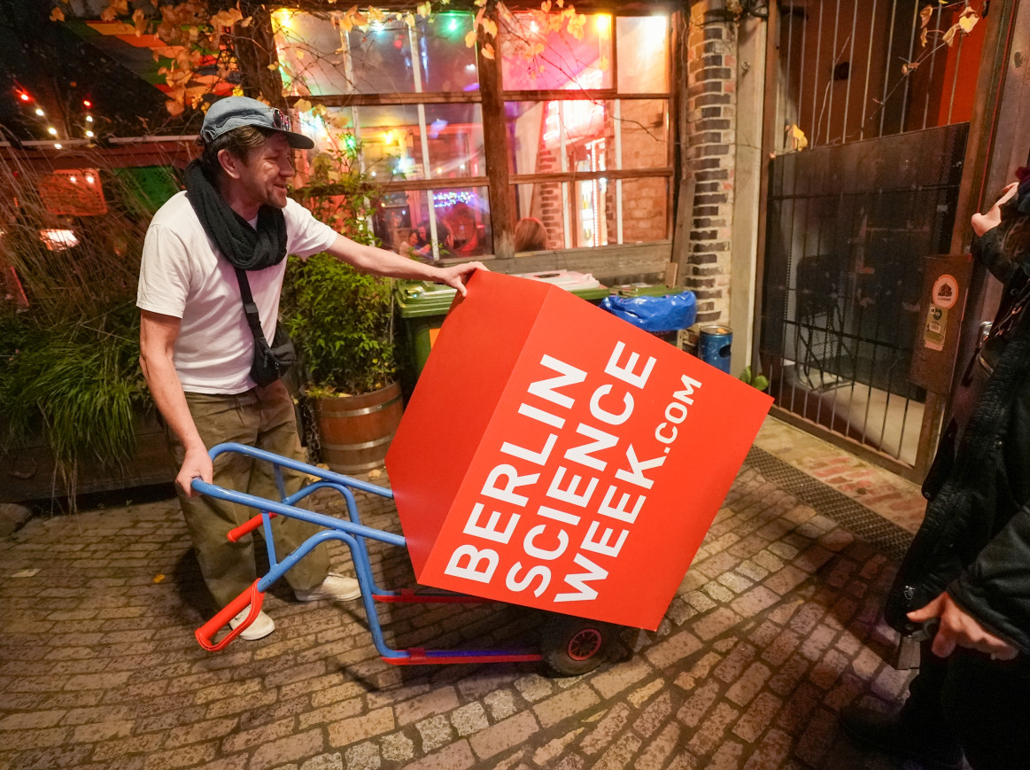 A man transporting a big red cube with the text "Berlin Science Week"