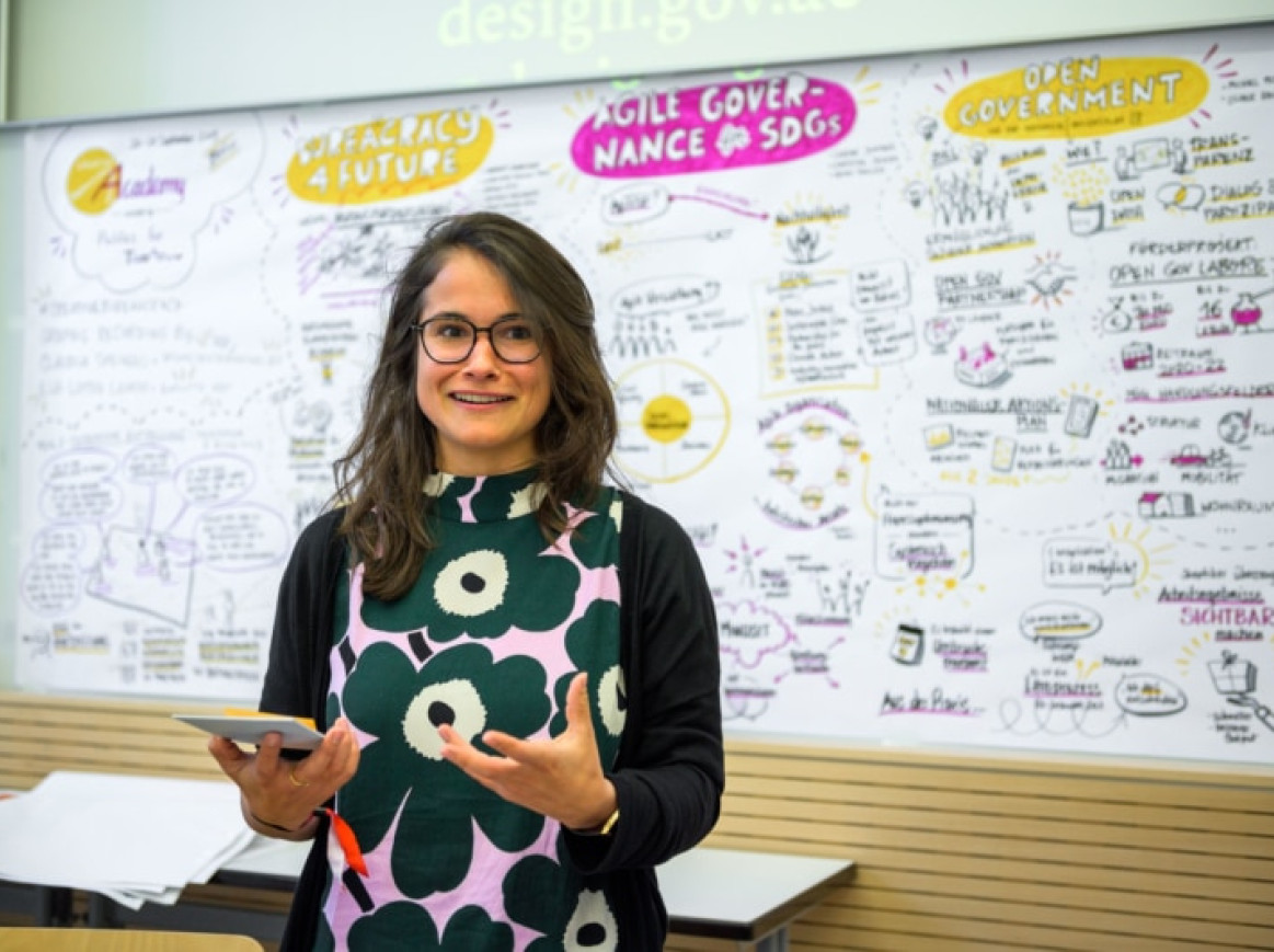 woman standing in front of a white board and talking 