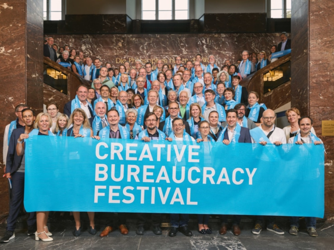 people standing on stairs and celebrating with a big creative bureaucracy festival banner 