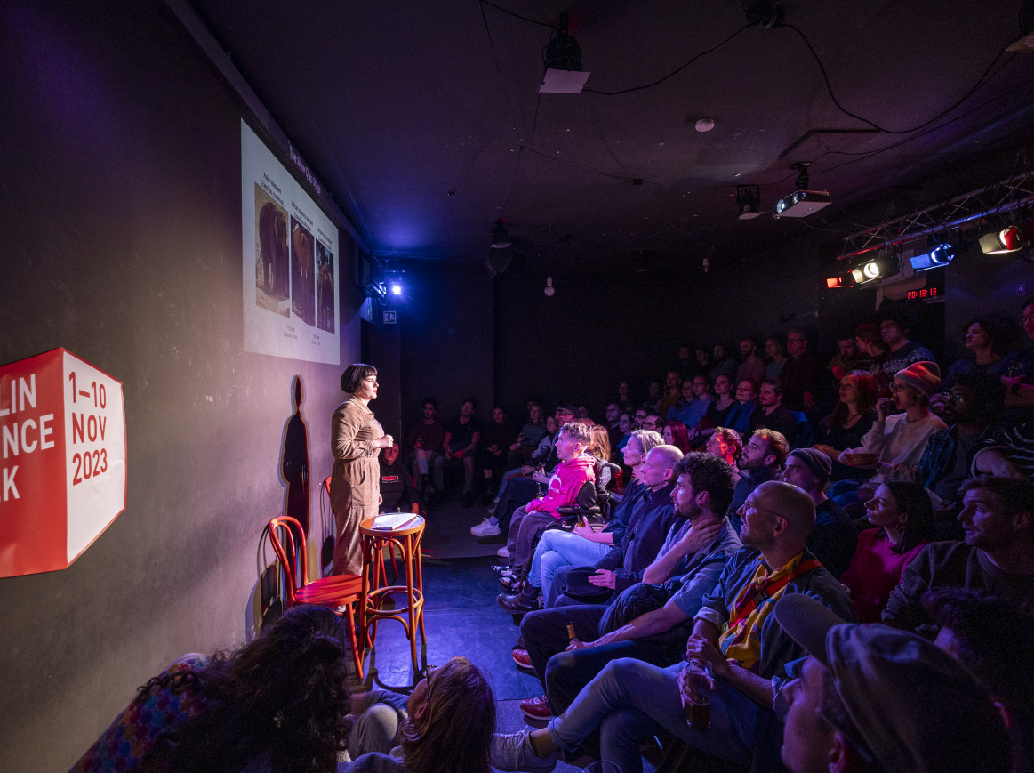 A woman stands on stage at a science comedy slam