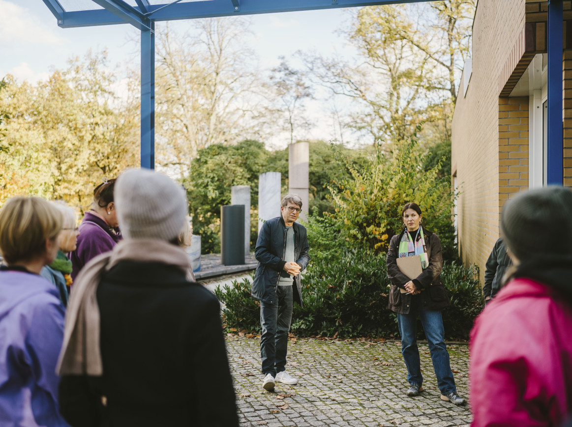 A group of people stands outside for a tour. 