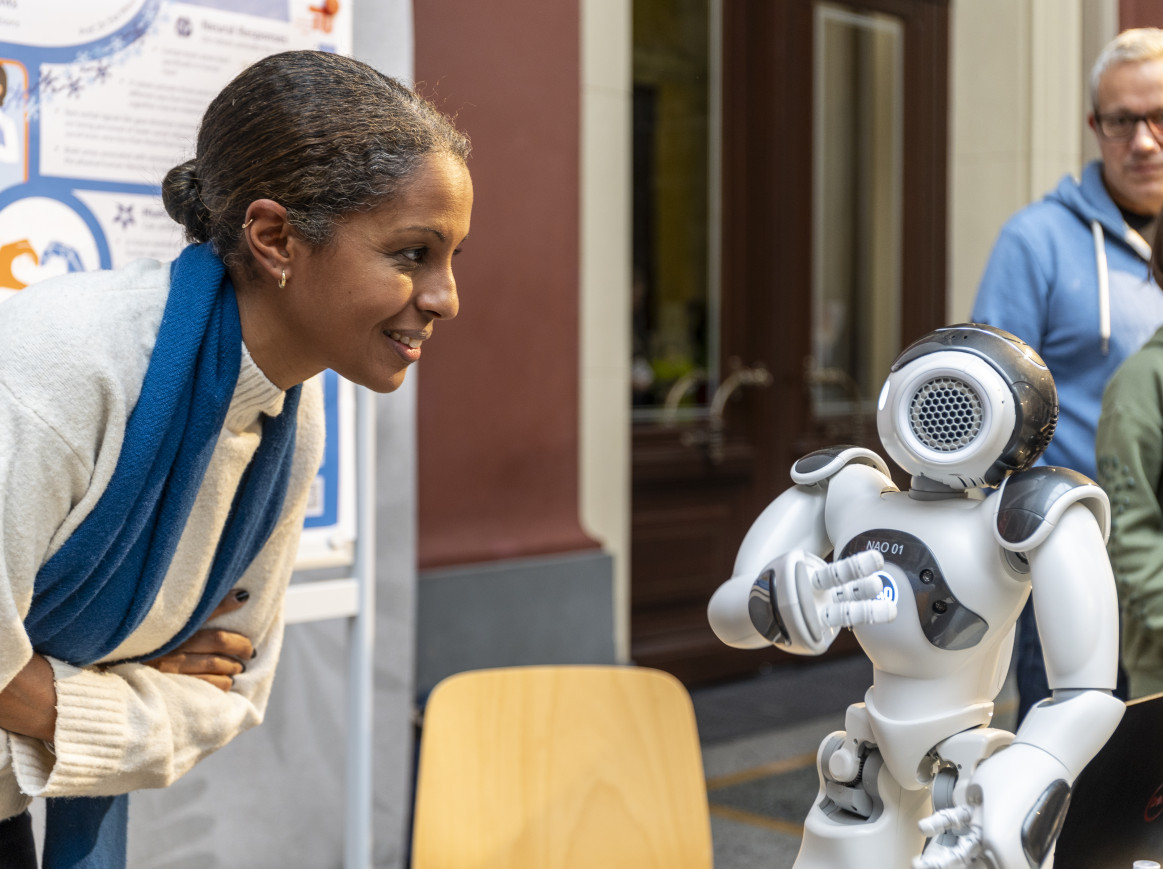 A woman engages with a small robot. 