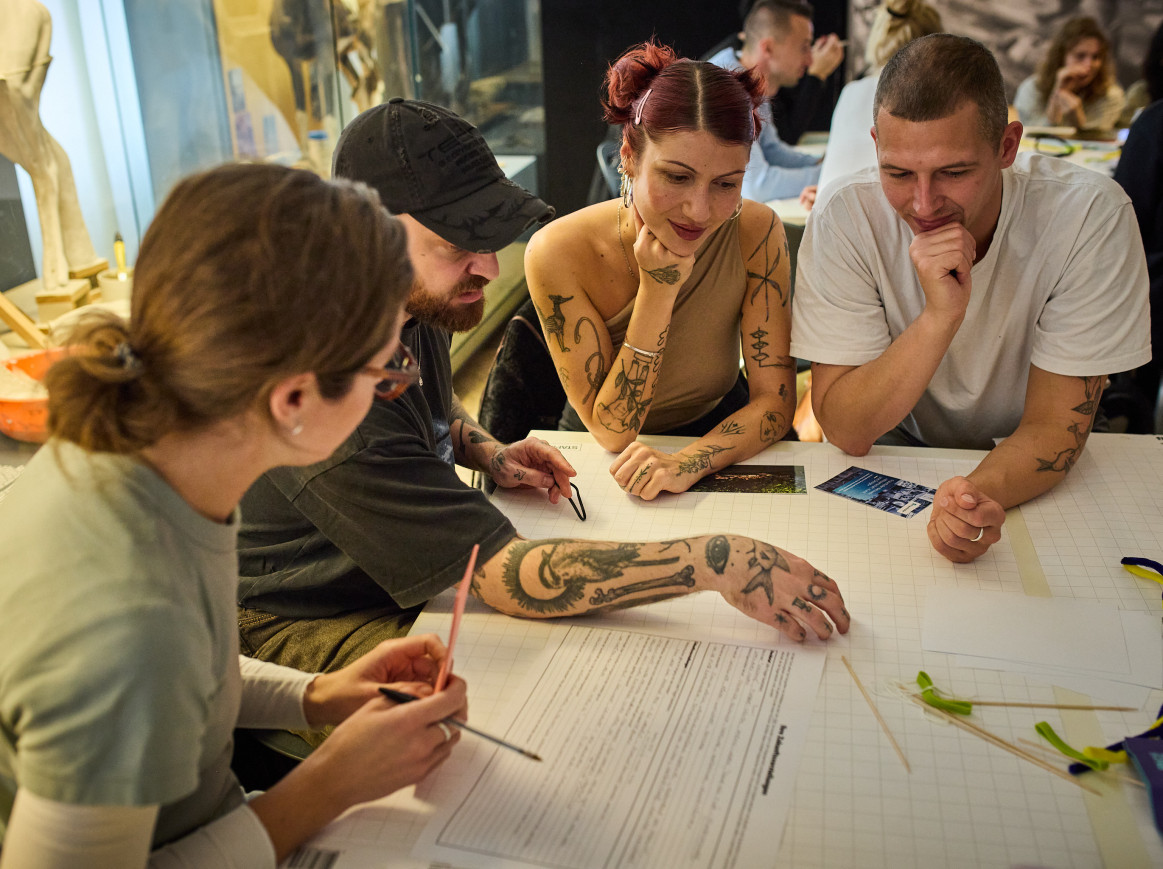People point at a document in a group sat at a table. 