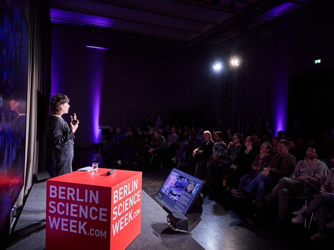 Someone speaks on a stage looking at a crowd. 