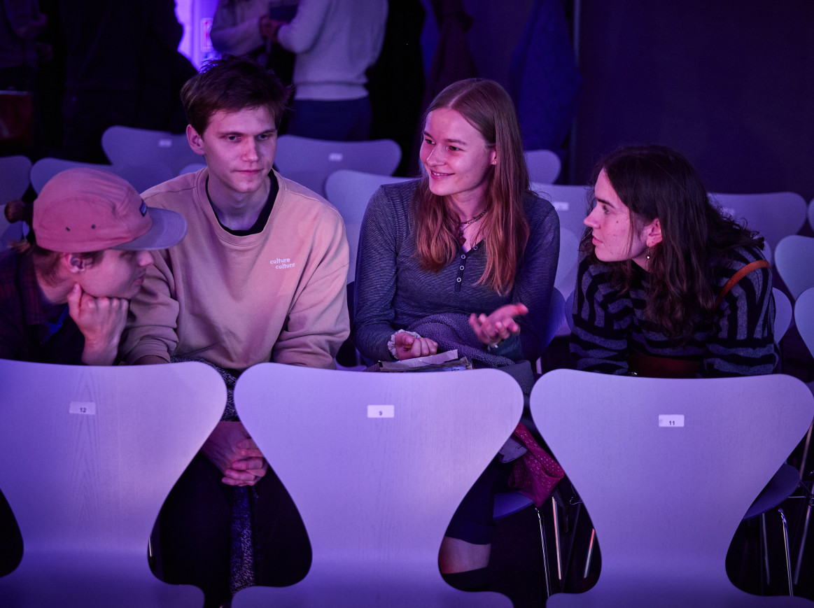 A group of students sit and smile at one another 