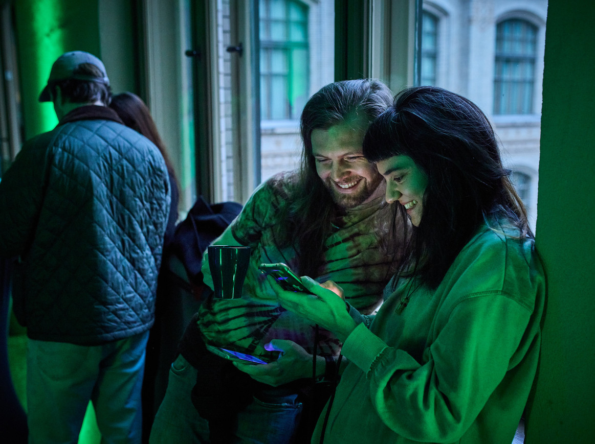 Two people smile at their phones