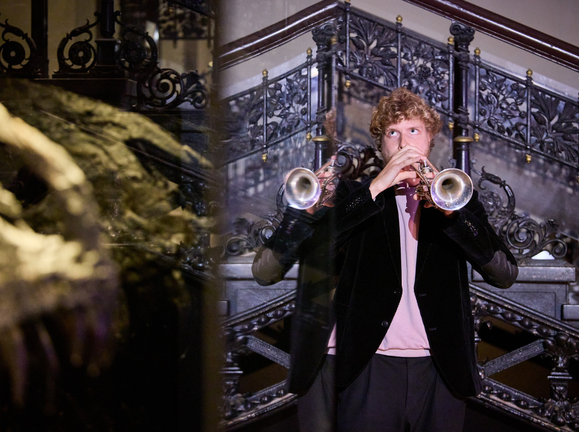 A man plays a trumpet in a museum. 