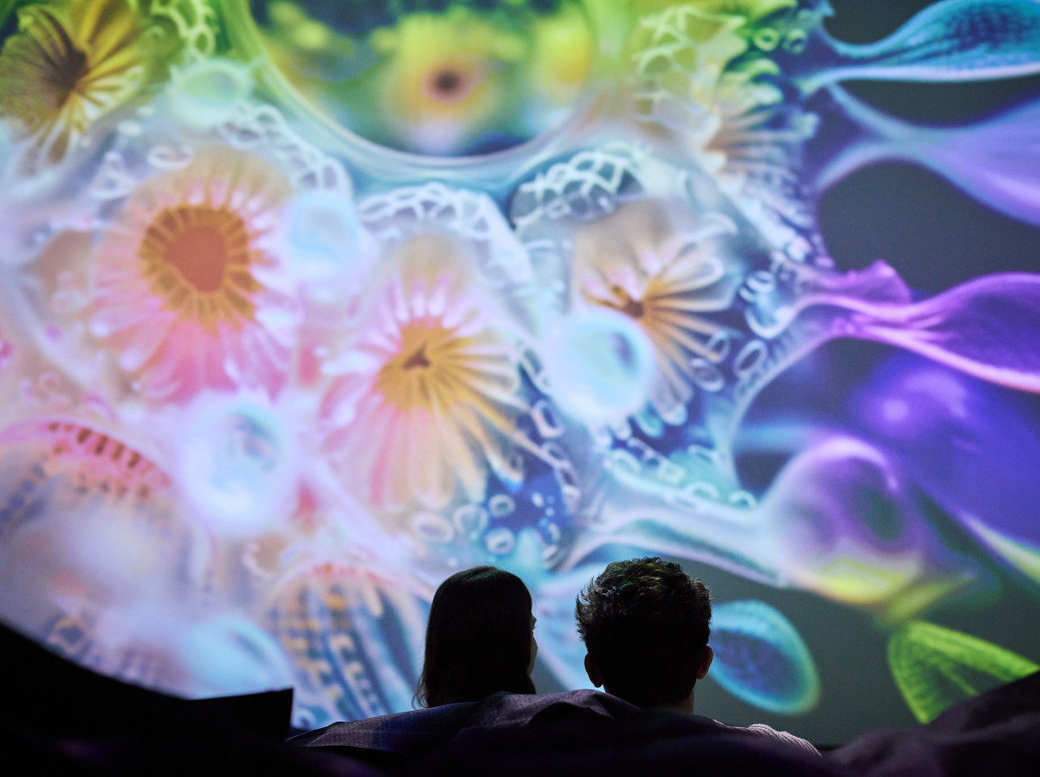 A couple sits in front of trippy visuals 
