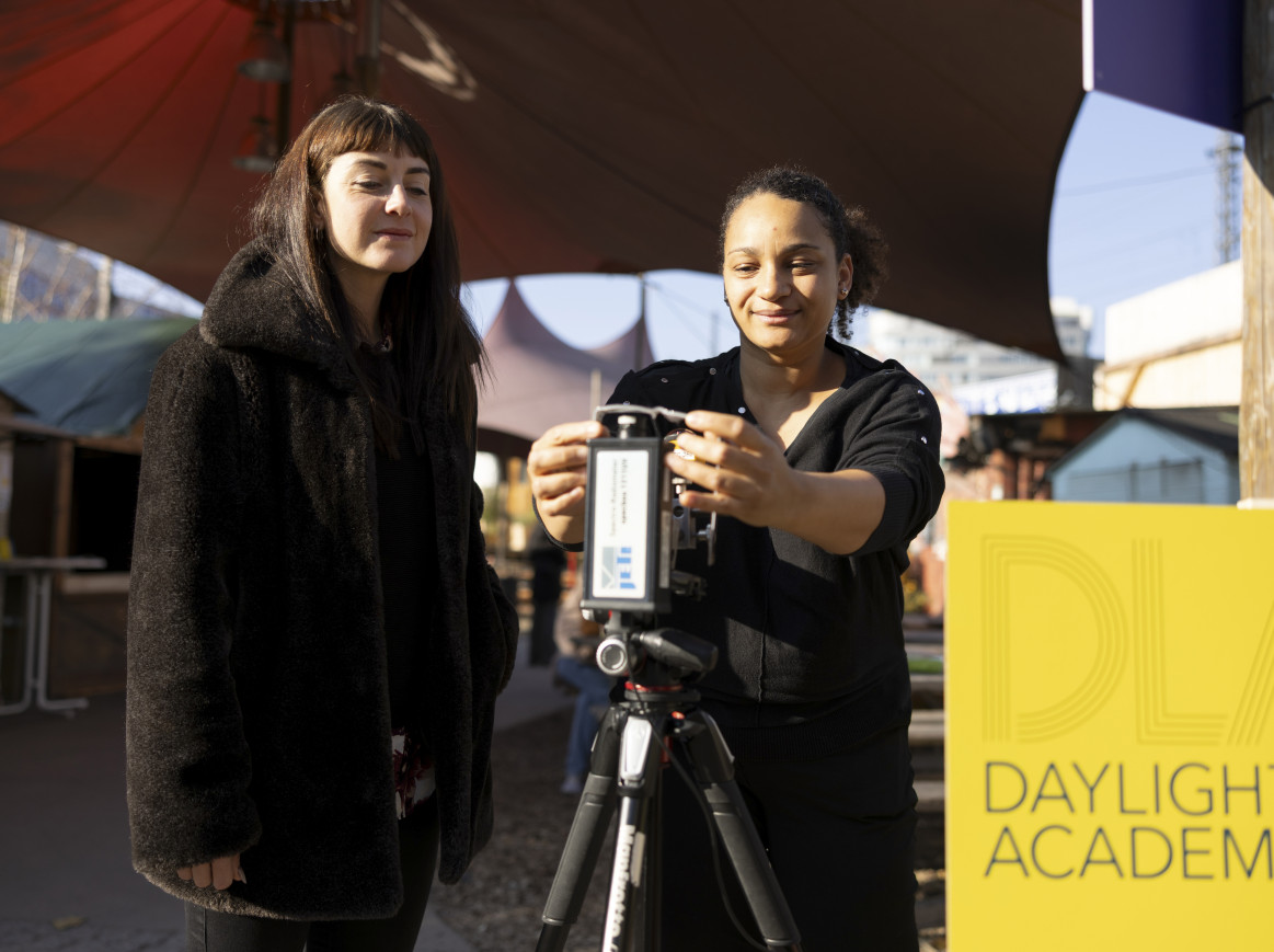 Two women holding an apparatus outside. 