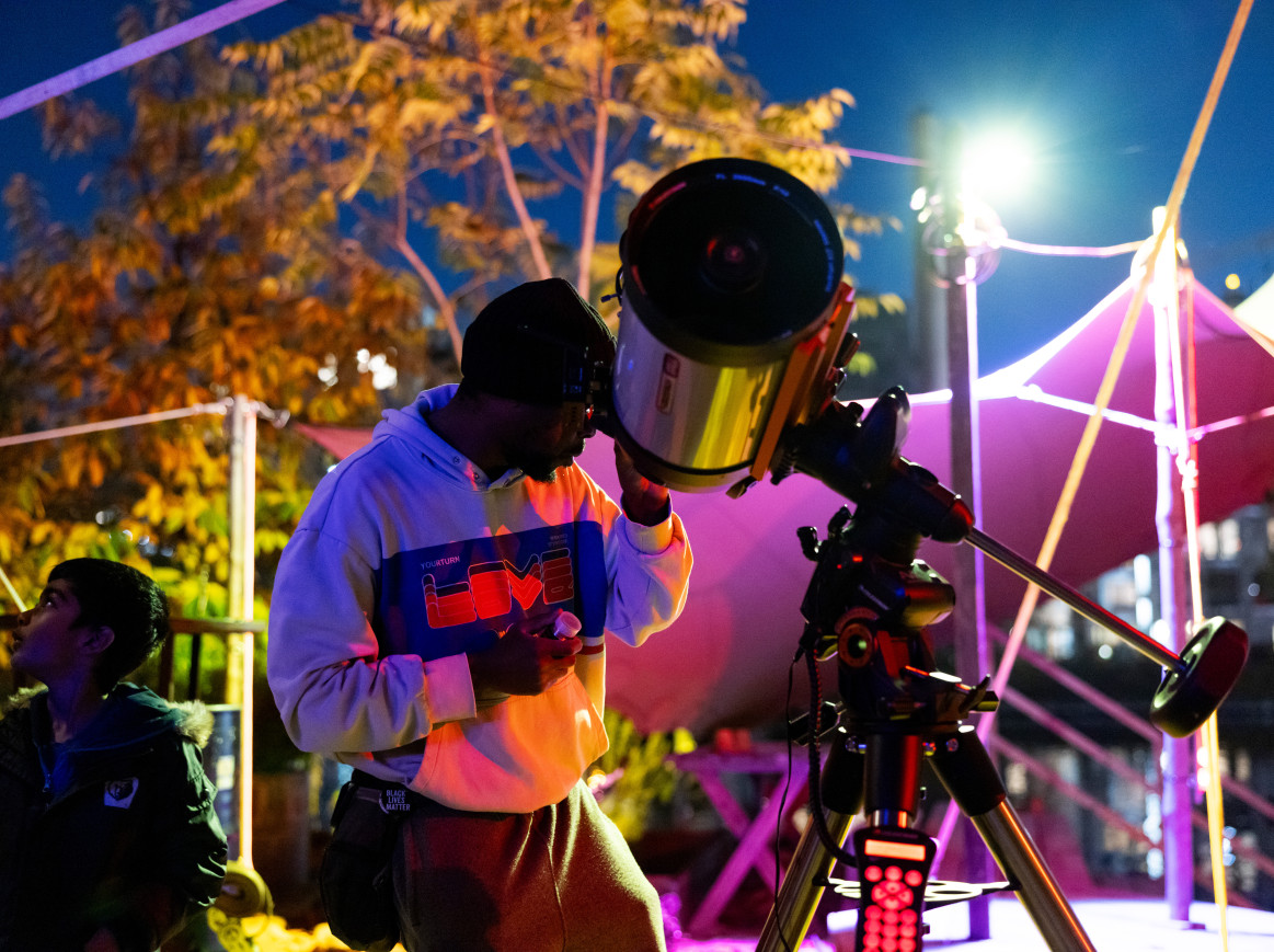 A man looks through a telescope