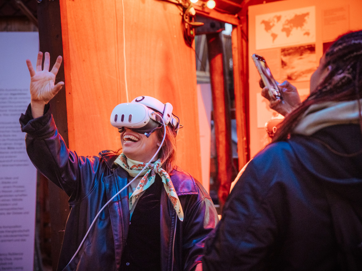 A person wearing a VR headset reaches their hand up
