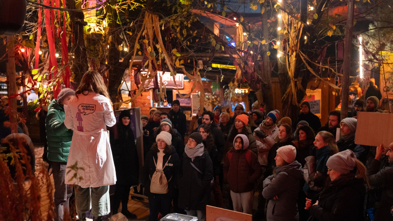 A crowd of people watching a person speaking outside.