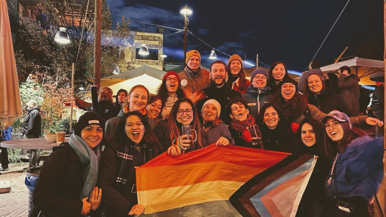 Soapbox Science Berlin and LGBTQ+ STEM Berlin teams pose with pride flag at Holzmarkt 25.