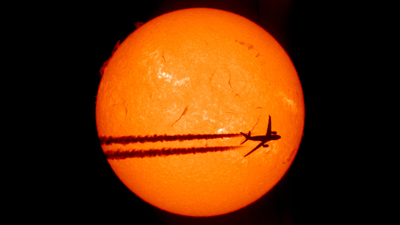 A plane crossing the sun, only its shadow visible