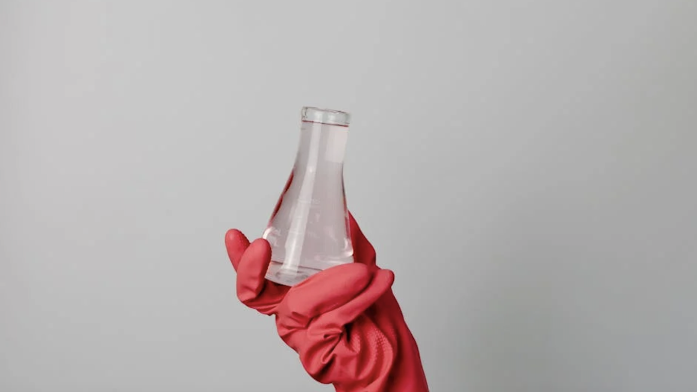 photograph of lab beaker being held by red glove