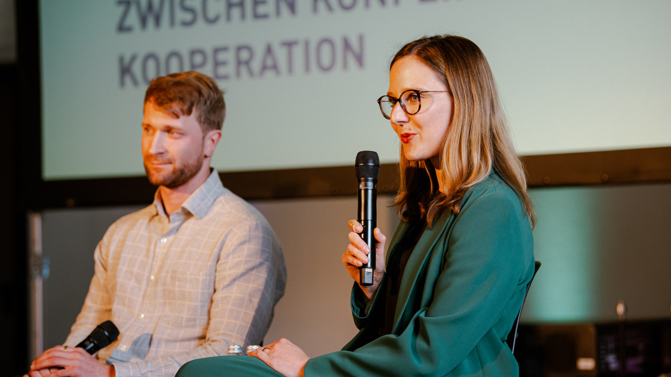 woman and man sitting on a stage holding a presentation