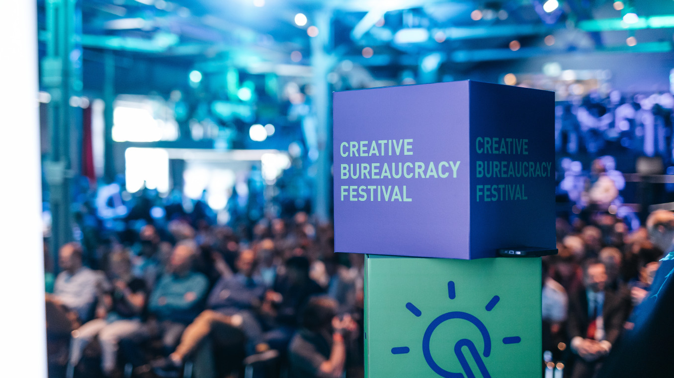 people sitting in the back in front of the stage (blurry) and the creative bureaucracy stage merch (dice) is in front 