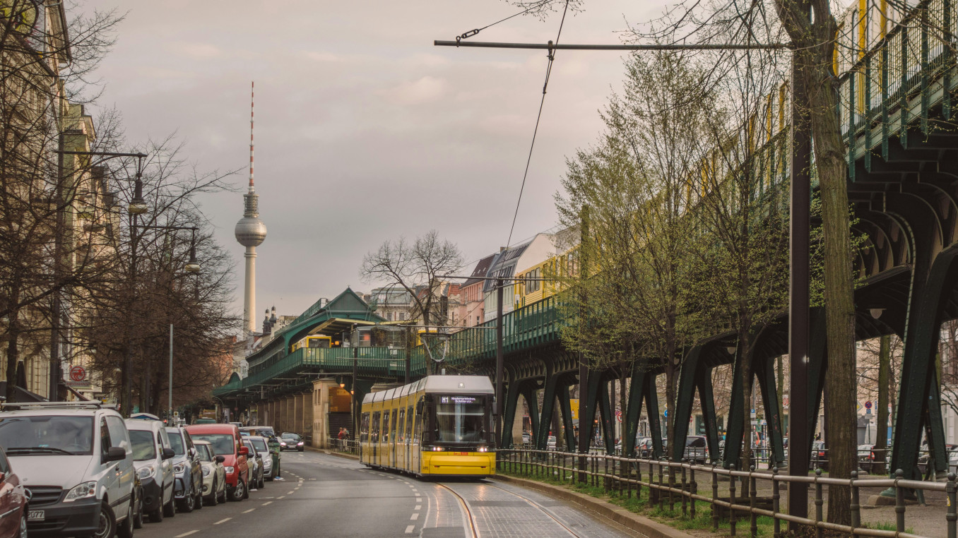 A tram drives through Berlin with the TV tower in the back. 