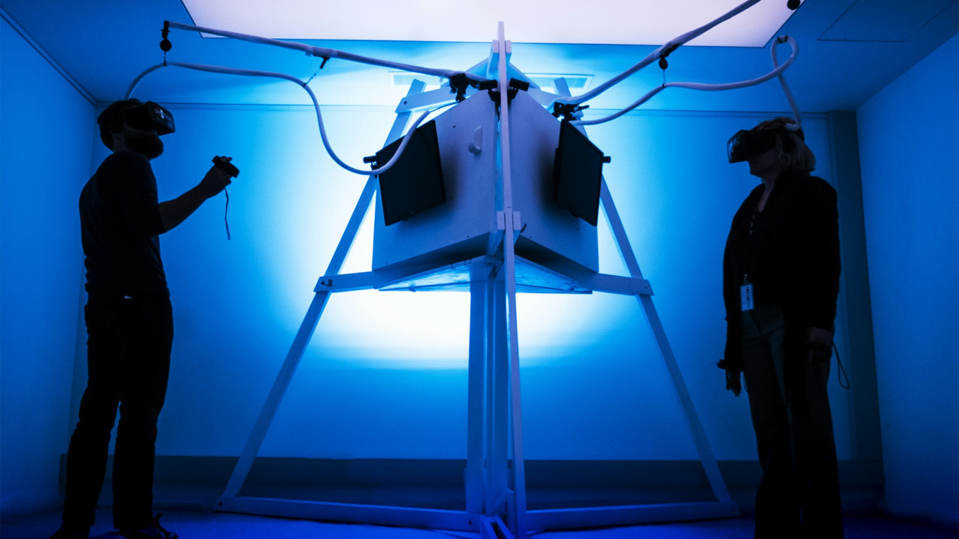 Two people with VR glasses on opposite ends of a machine. 