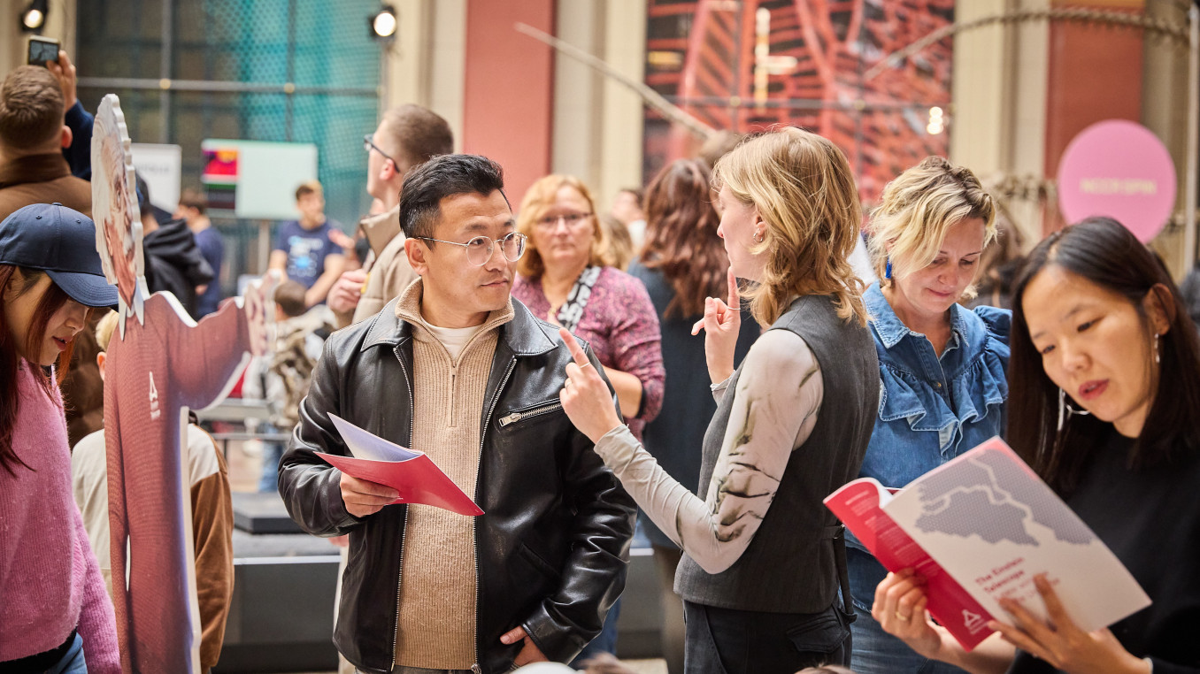A woman explains something to man with a brochure in a museum.