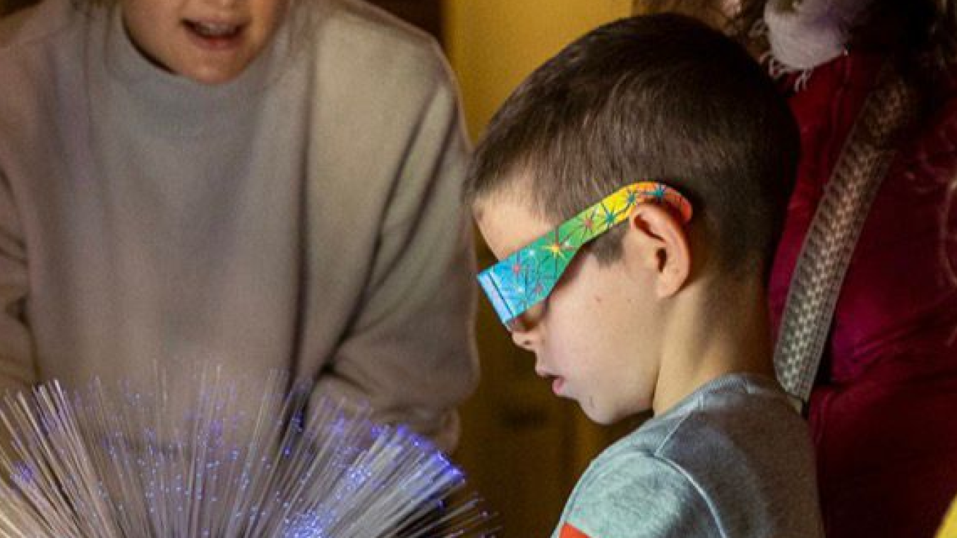A boy with refractive glasses staring into a fiber guided light source.