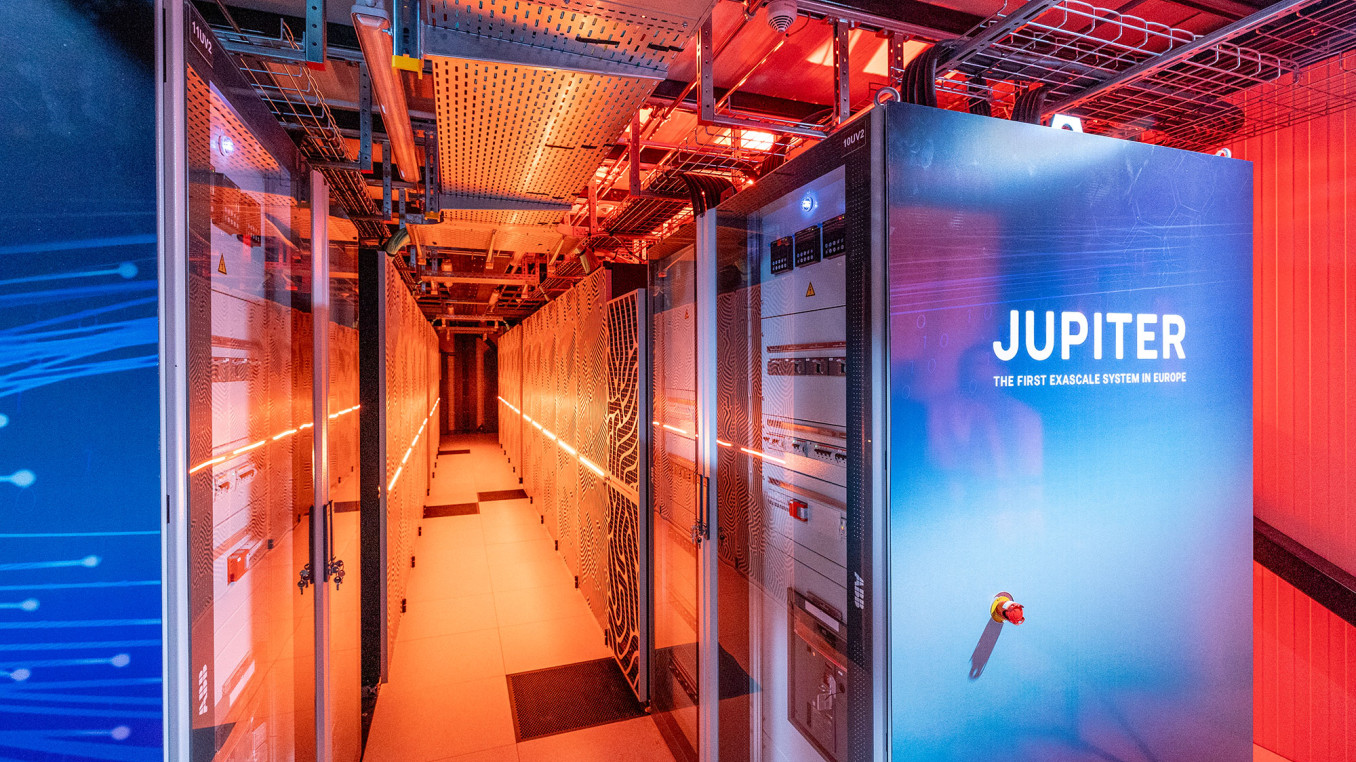 Zwei große, vertikale Rechnerschränke mit den Aufschriften 'JUPITER' in blauen und weißen Farbtönen. Der Raum ist mit orangefarbenem Licht beleuchtet.