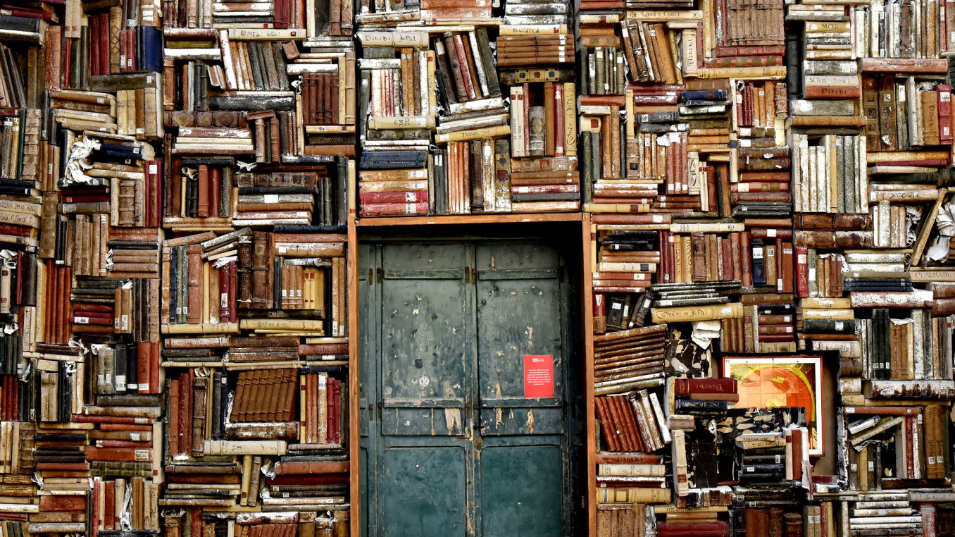 wall with door and bookshelves crammed with books 