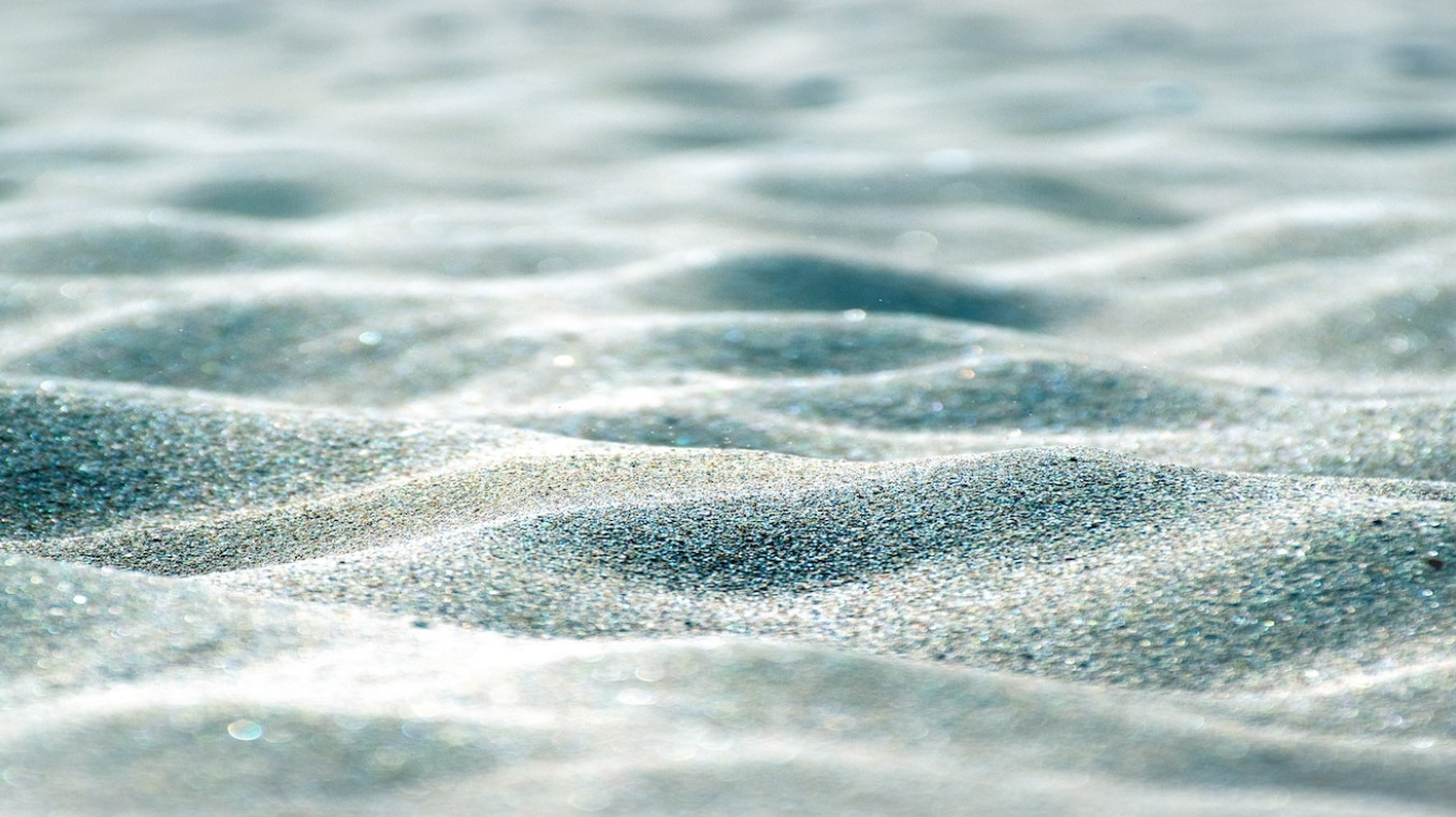 Close-up view of rippled sand with soft light and shadows.