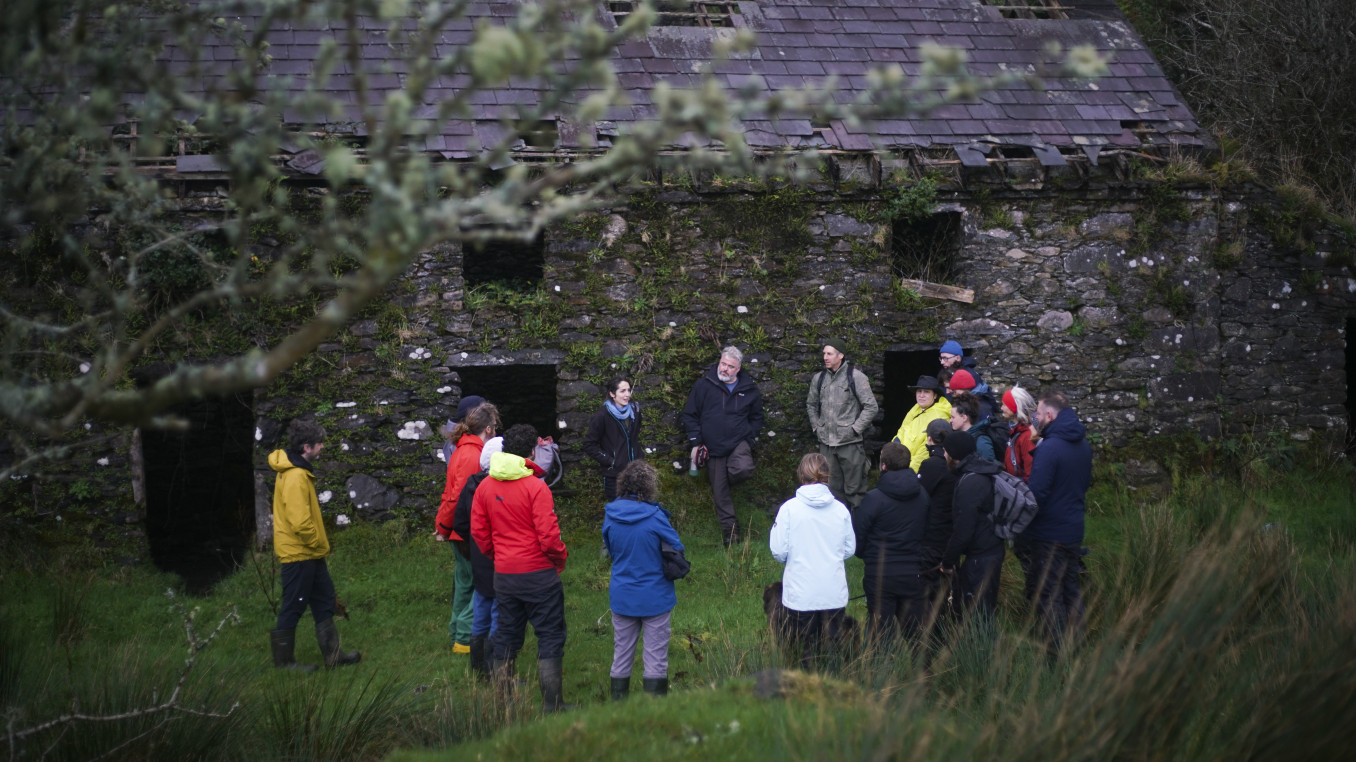 Image of a group standing outside an old stone cottage in the Irish uplands