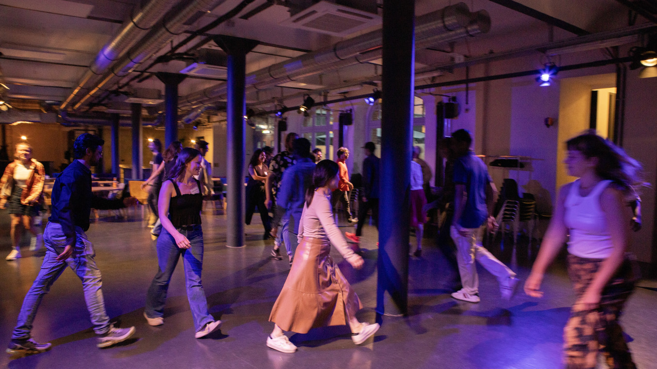 Workshop participants moving around a room with dim purple lighting 