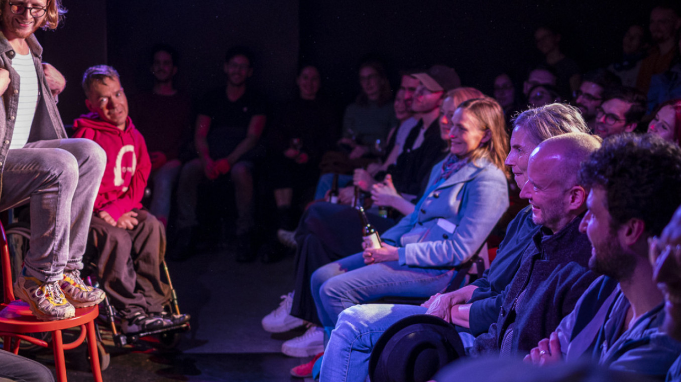 Comedians do impression of birds on stage in front of laughing audience.
