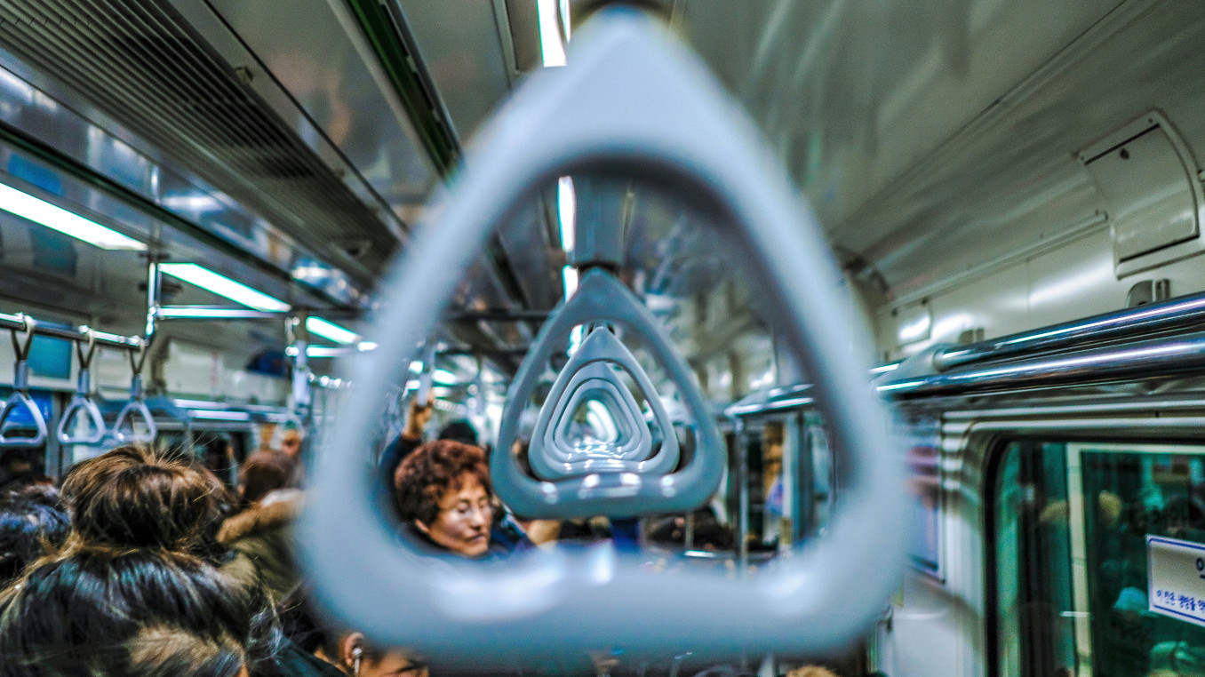 A subway handle in a crowded subway car