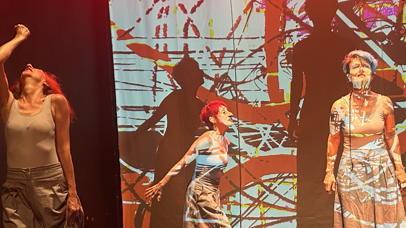 Three performers in front of an abstract video projection